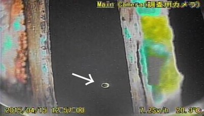 １号機格納容器の底部にたまっているとみられる水（黒い部分）。撮影したロボットの丸いライトが水面で反射し、揺らいでいた（矢印）＝４月１５日、東京電力福島第１原発（東電提供）